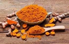 Tumeric powder in a bowl surrounded by Turmeric root & Science